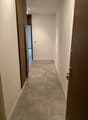 Empty hallway with two doors, tiled floor, white walls, ceiling lights