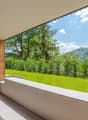 Wooden panels, concrete floor, grassy garden, plants, railing, shadow on floor, distant mountains