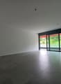 Spacious open-plan living room with large windows overlooking a green outdoor area, hardwood floors, and minimalist decor