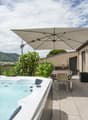 hot tub with umbrella, tiled floor, plants, table, chairs