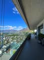 Terrace with glass railings, view of city and mountains, table, chairs, plants, and trees