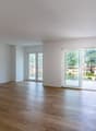 Spacious living room with large windows, hardwood flooring, and access to a balcony or terrace overlooking the surrounding neighborhood