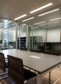 modern office interior with long table, glass walls, chairs, white ceiling, art pieces on the walls