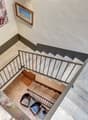 Two-story house, marble floors, staircase, black modern chairs, framed painting on the wall.