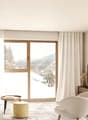 neutral color scheme, large windows, couch, armchair, coffee table, TV, wooden entertainment center, rug