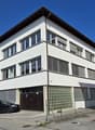 Three-story building, white exterior, garage, red Swiss flag on the wall