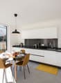 modern kitchen, white cabinets, black countertops, stainless steel appliances, dining table, chairs