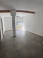 Empty room with white walls, gray tiled floor, wooden beam on ceiling, window with blinds, and an air conditioning unit.