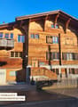 Large wooden house with several floors, wooden balcony, and a staircase leading to the entrance.