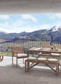 wooden furniture, table with benches, balcony with railings, potted plants, distant mountain range