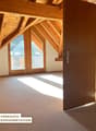 empty attic room with wooden ceiling, carpeted floor, large windows, open door