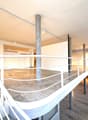 Empty room with concrete floor, white railing on the second floor, several pillars, lamps on the ceiling