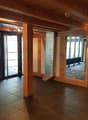 Empty room with wooden beams, tiled floor, glass doors, radiator, surveillance camera
