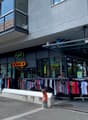 Large building with glass facade, clothing store, metal awning, rack with clothes