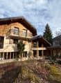 two-storey chalet made of wood, multiple balconies, panoramic windows, located on the hillside with forest and mountain view