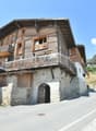 Stone and wooden building, balconies, doors, windows, archway entrance, concrete road