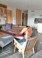 living room with sofa, coffee table, bookshelves, dining table, chairs, lamps, kitchen, cabinets, microwave