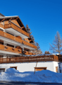 Modern multi-level building, wooden balconies, brick facade, snow-covered ground
