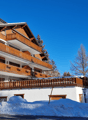 Modern multi-level building, wooden balconies, brick facade, snow-covered ground