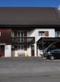 2 story house, brown roof, balcony, wooden fence, 2 parked cars, 2 cars sheltered by carport, garden bench, sofa, chairs