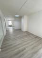 Empty room, hardwood floors, white walls, high ceilings, two columns, windows