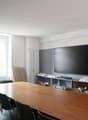 conference room, long wooden table, chairs, mounted TV, curtains, window, floor lamp