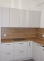 modern kitchen with white cabinets, wooden countertops, white drawers, a stove, and a sink