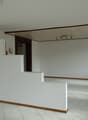 Empty room with white walls, white tiled floor, wooden trim, and a ceiling with lights.