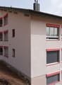 Modern apartment building with multiple windows, red trims, and a chimney on top