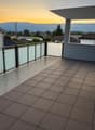 large balcony, black railing, white panels, tiles, mountain view