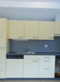 modern kitchen with white cabinets, black countertops, stainless steel sink, dishwasher, electric oven