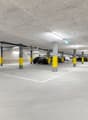 concrete floor, yellow pillars, multiple parking spots, white directional arrows