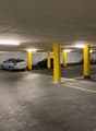underground parking lot with yellow pillars, 4 cars parked, bicycles parked on the side
