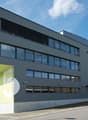 modern office building, gray exterior, glass windows, yellow accents, parking lot