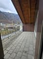 balcony with tiled floor, wooden ceiling, metal railings, view of mountains and buildings