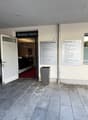 Entrance to a business center with an open door, a red carpet, a trash bin, and a signboard with the text 'Business Center'.