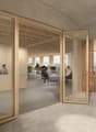 The image shows a modern and open office space with a reception area and several workstations. The office has a minimalist design with wooden beams and glass walls, providing a bright and airy atmosphere. The Oxus logo is visible on the glass wall, indica