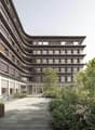 modern architecture, concrete, large windows, parking area with bicycles, greenery