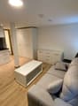 open floor plan, gray couch, white coffee table, kitchen, white cupboards, hardwood floor