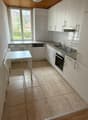 white cabinets, tile floor, white table and chairs, large window, gas stove, sink, dishwasher, heating unit