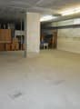 Large open basement space with concrete floor, exposed ceiling, and storage boxes and furniture items along the walls.