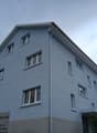 Large blue apartment building with windows, roof gutter, gray foundation, sign reading 'Nur für Berechtigte' on the left side