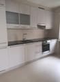 modern kitchen, white cabinets, black countertops, stainless steel appliances, marble floors