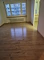 Empty room with white walls, white ceiling, wooden floor, large window with white shutters, white radiator