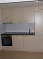 a kitchen with cream cabinets, tiled floor, sink, and oven