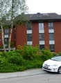 red brick building, 3 stories, white framed windows, balconies, greenery