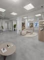 interior room, clean minimal design, gray floor, white walls, glass door, couches, center table, shelves, plants