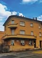 3 story building, yellow facade, chimneys, balconies, windows, door, fence, street