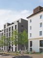 3-story apartment building with 12 units, modern design, white exterior, balcony, trees and shrubs landscaping