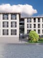 A modern, multi-story apartment building with a clean, minimalist design. The building features a rectangular shape with multiple floors, large windows, and balconies on each floor. The exterior is predominantly gray in color with some accent colors in th